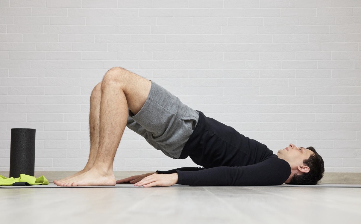 Man performing glute bridge exercise at home