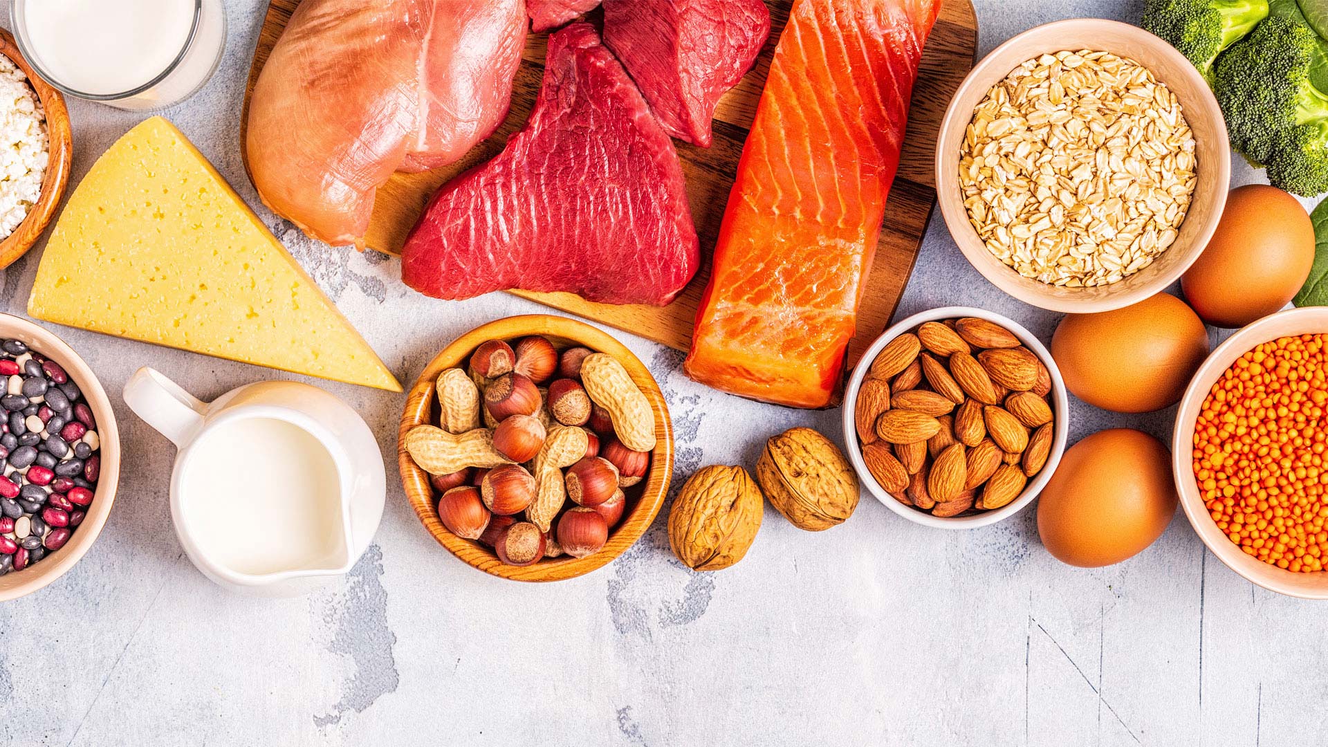 Variety of high-protein foods including meat, fish, eggs, nuts, and dairy