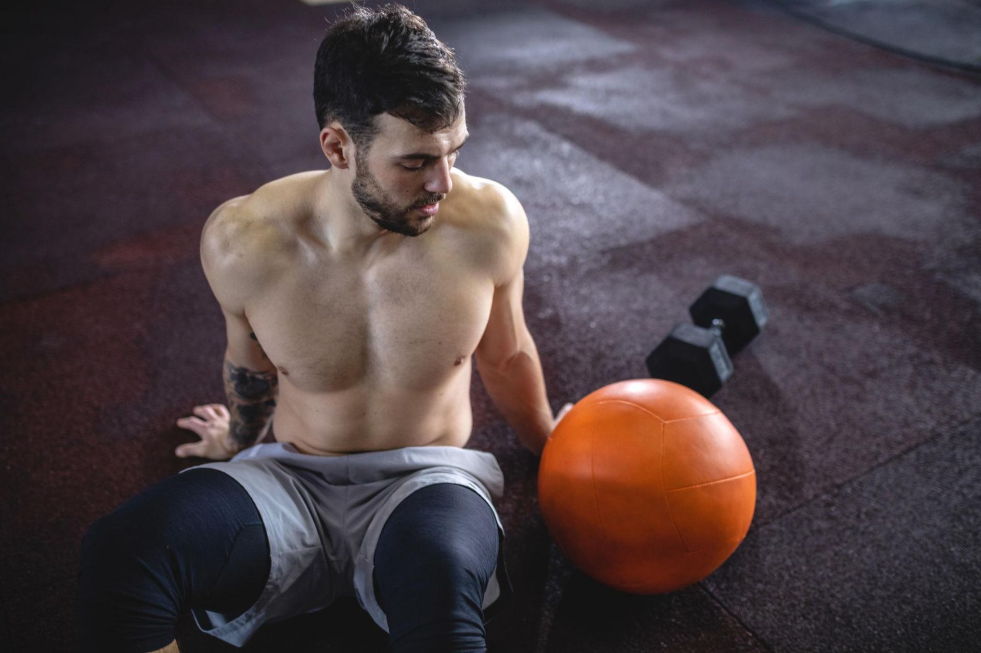 Man sitting on gym floor recovering between sets