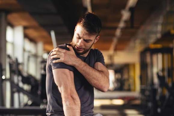 Man holding his shoulder in pain at the gym