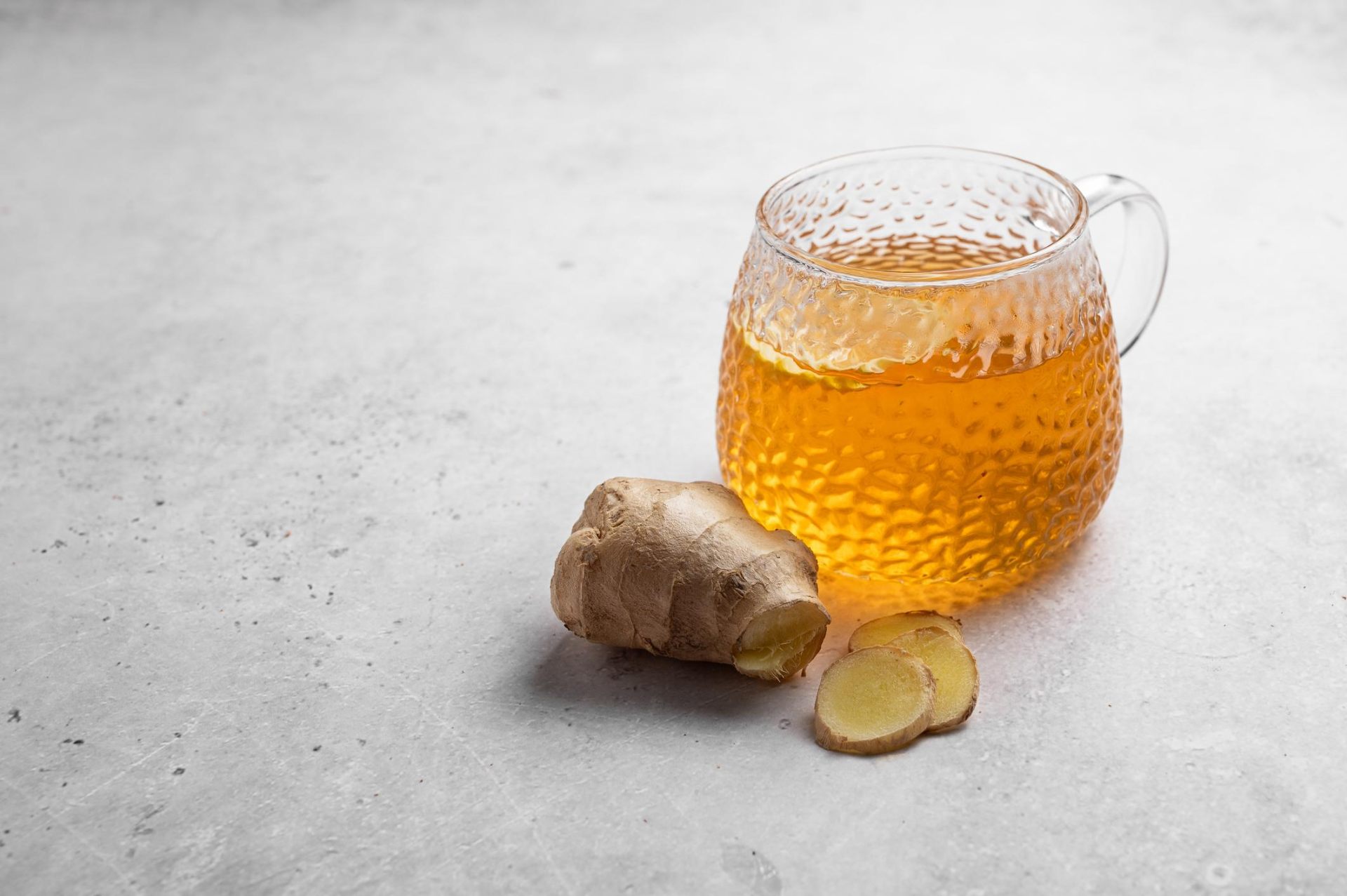 Glass cup of ginger tea with fresh ginger root